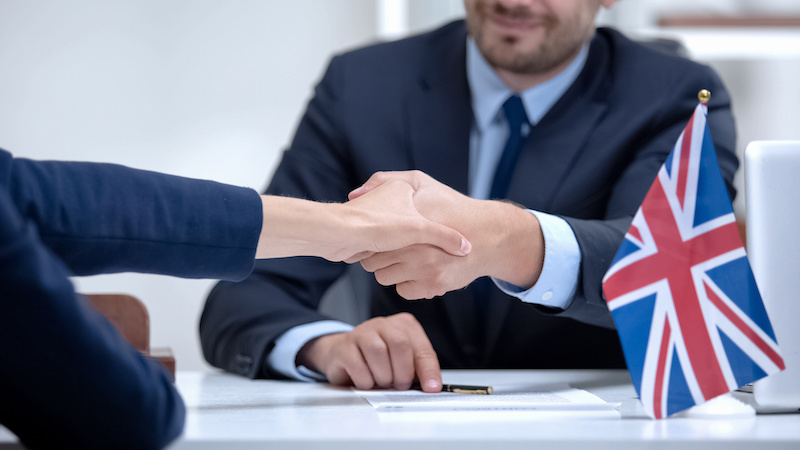 British businessman signing contract with international partner, shaking hand business meeting discussing accounting seed and MTD