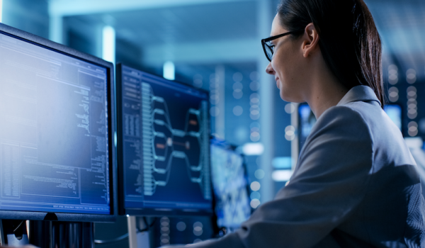 Photo showing woman coding on computers in dark room