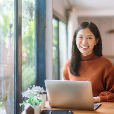 Happy young woman at a coffee shop with a laptop