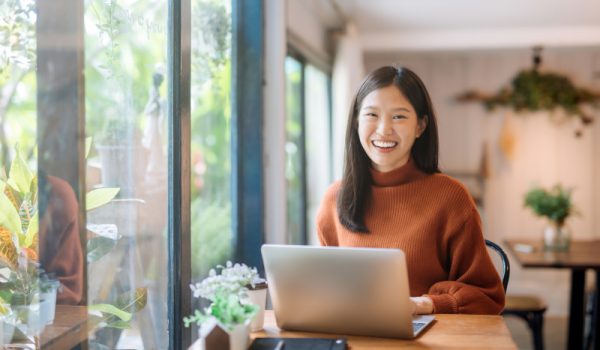 Happy young woman at a coffee shop with a laptop