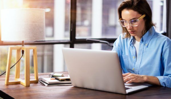 Woman working with a laptop with lamp on desk