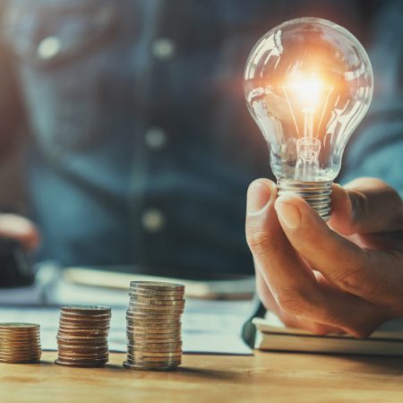 accountant counting coins and holding a lit lightbulb