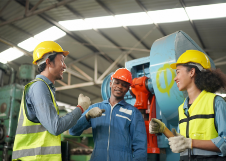 Field and service workers fist bumping in factory